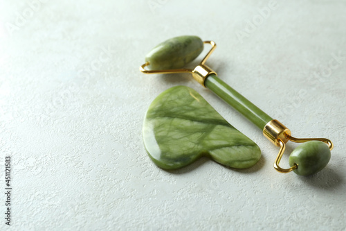 Face roller and gua sha on white textured background