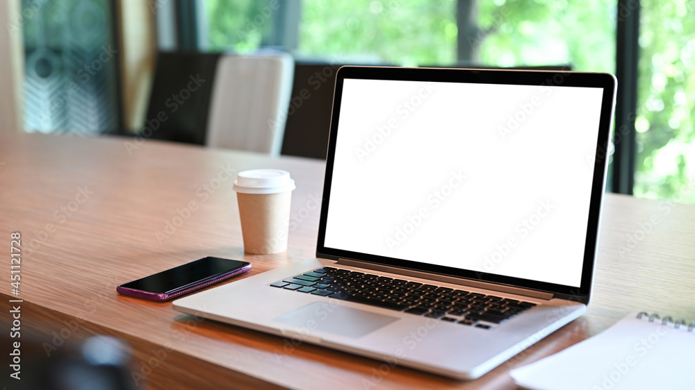 Close up laptop computer with white screen, mobile phone and coffee cup on wooden table. Close up laptop computer with white screen, mobile phone and coffee cup on wooden table.