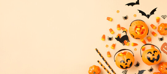 Top view photo of halloween decorations pumpkin baskets candy corn straws spiders web bats and black cat silhouettes on isolated beige background with copyspace