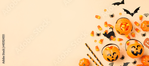 Top view photo of halloween decorations pumpkin baskets candy corn straws spiders web bats and black cat silhouettes on isolated beige background with copyspace photo