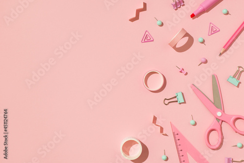 Top view photo of school supplies pastel pink and green stationery adhesive tapes pushpins binder clips scissors pencil felt pen and ruler on isolated light pink background with copyspace