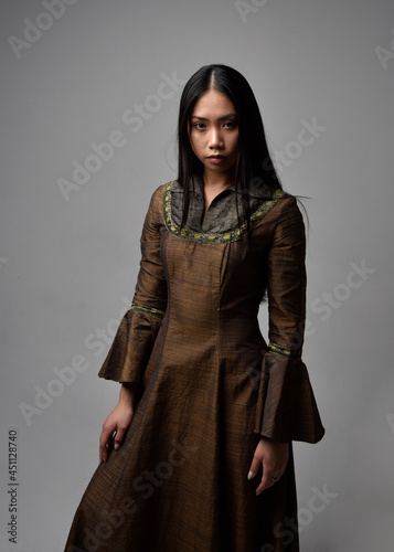 Close up portrait of beautiful young asian woman with long hair wearing medieval fantasy gown. Graceful pose with gestural hands, isolated on studio background.