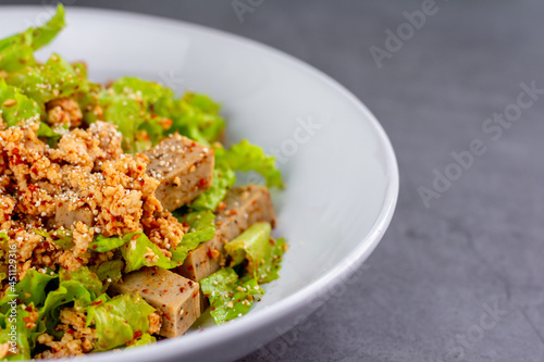 Thai spicy Vietnamese sausage with minced chicken, fish sauce, lime juice, lettuce salad on a white plate.