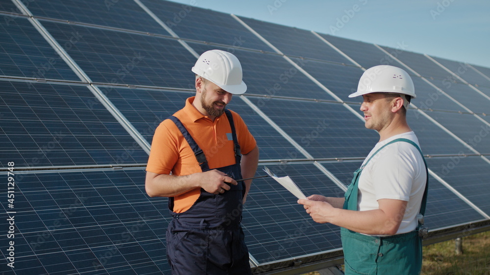 Technician of energy checking the solar cell panels at solar farm energy.  Solar energy from Sun inverter to Electricity of Factory. An employee of a  power plant transmits commands by walkie-talkie. Stock