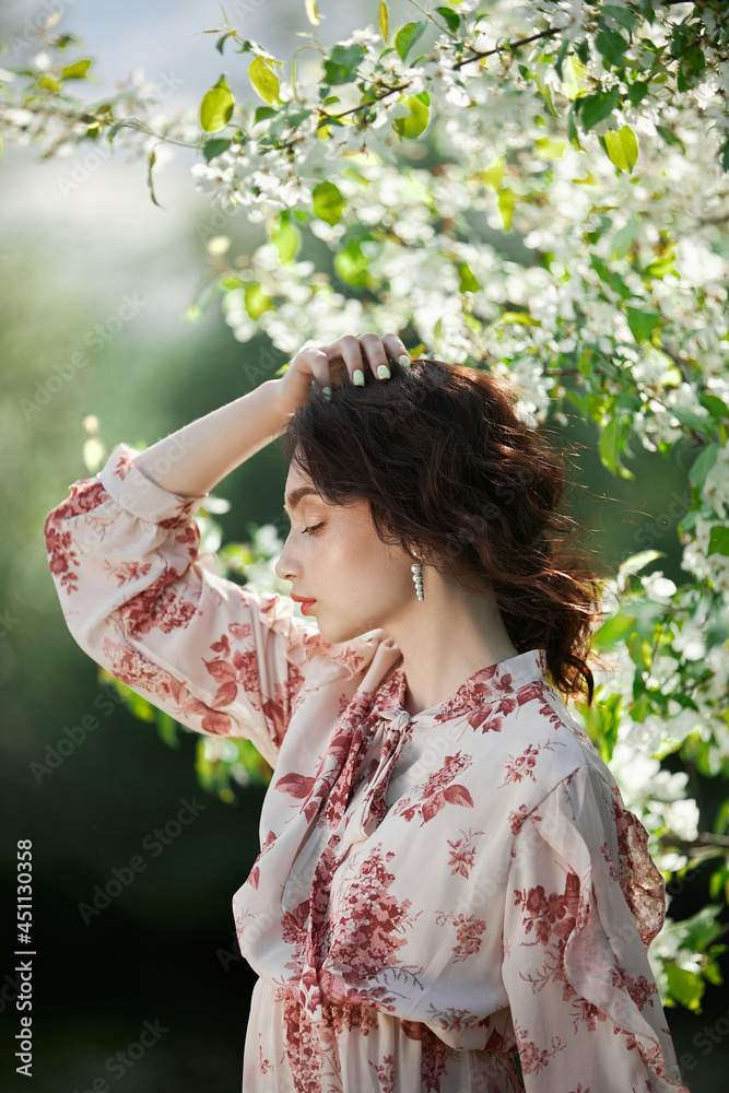 Beautiful romantic woman stands in branches of blooming apple tree. Spring portrait girl in flowers apple tree Beautiful romantic woman stands in branches of blooming apple tree. Spring portrait girl in flowers apple tree