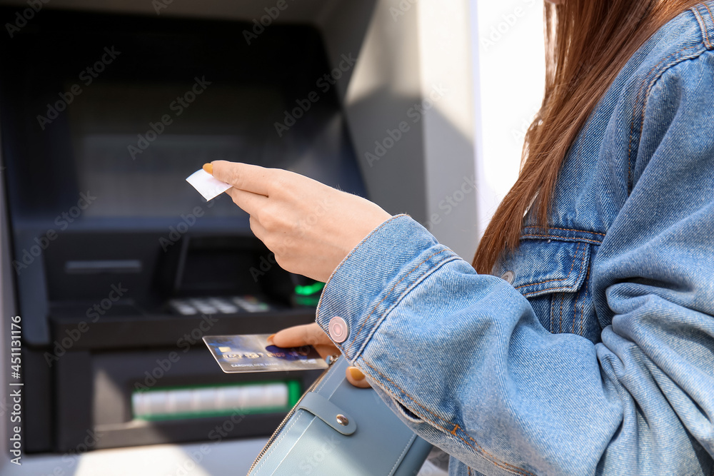 Young woman using ATM, closeup