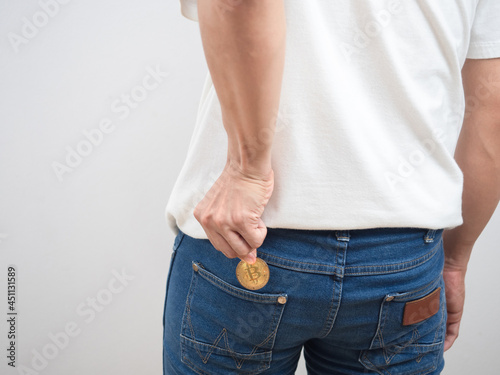 Close up back of man pick up golden bitcoin out of trousers jean pocket