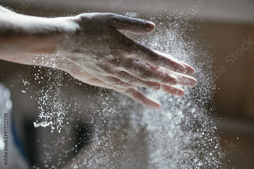 Glowing particles of flour in the air and a woman s hand close-up  photo of a hand in motion  blurred background