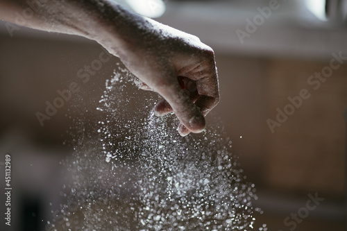 Flour wakes up from unclenched hand, close-up photo, blurred background