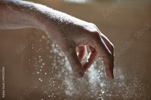 Girl scattering flour  close-up photo of her hand with grains of flour  horizontal background with the cooking process