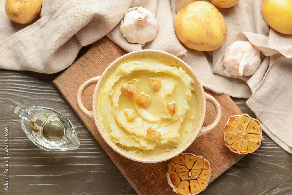 Pot of tasty mashed potatoes with garlic and vegetables on wooden background Pot of tasty mashed potatoes with garlic and vegetables on wooden background