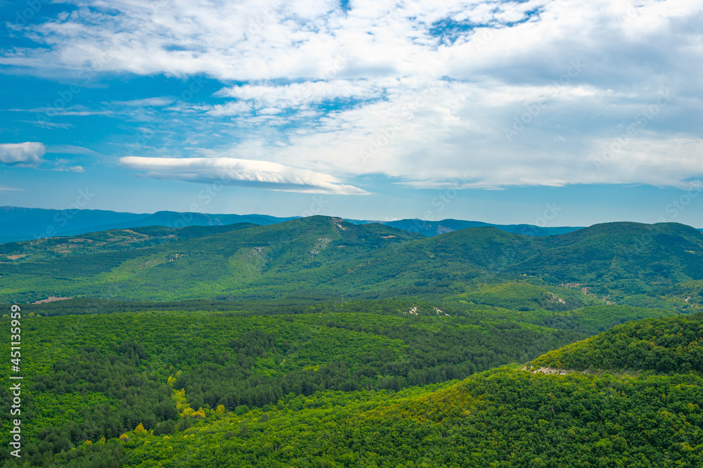 Crimean mountains covered with green forest against a blue sky with white clouds