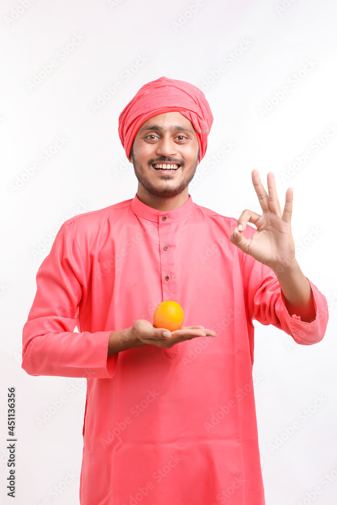 Indian farmer holding an orange fruit in hand over white background. Indian farmer holding an orange fruit in hand over white background.