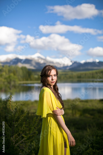 beautiful girl, brunette in a yellow dress walks near a mountain lake © AKaltykova