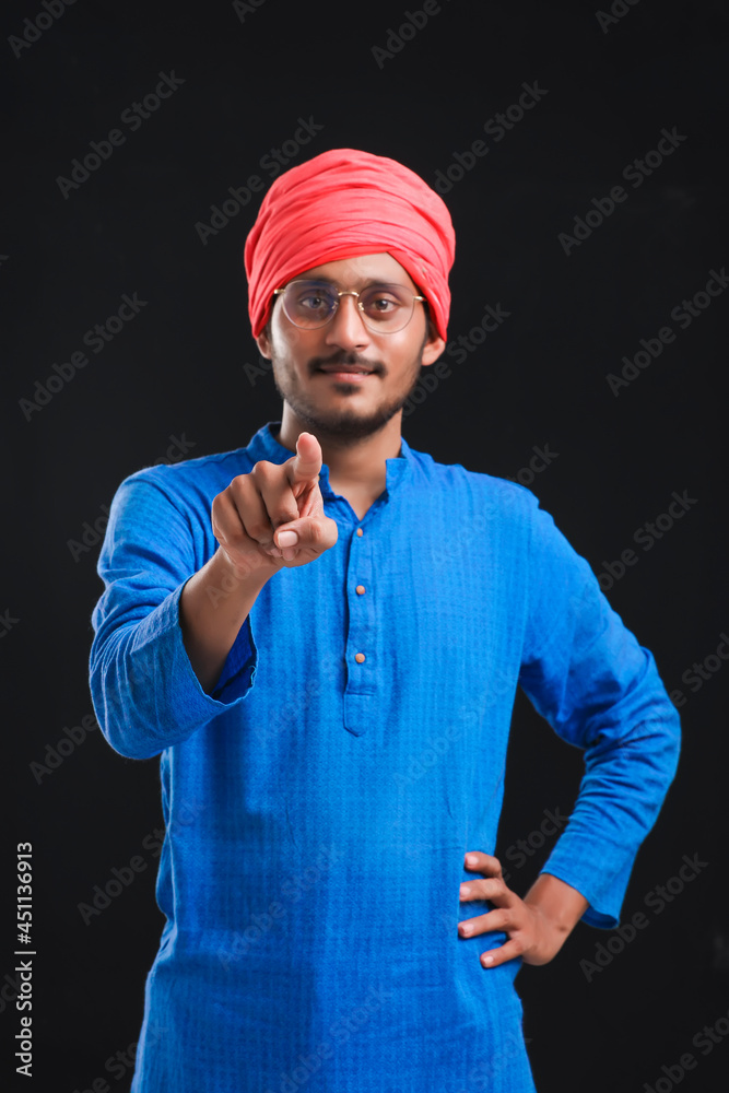Naklejka premium young indian farmer giving pointing with finger expression.