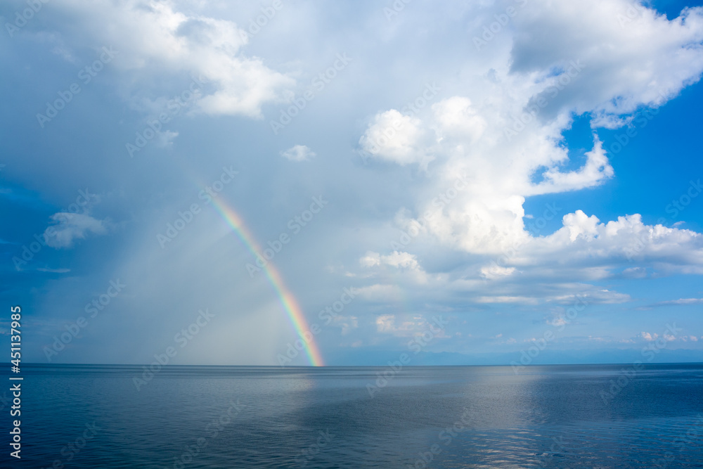Rainbow with cumulus clouds over Lake Baikal. Horizontal image.