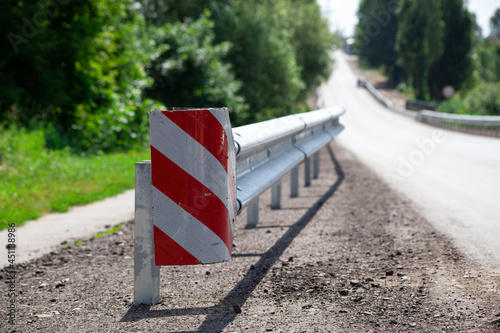 red road reflectors along the road. metal road fencing of barrier type, close-up. Road and traffic safety. reflective paint on sign. Median barrier photo