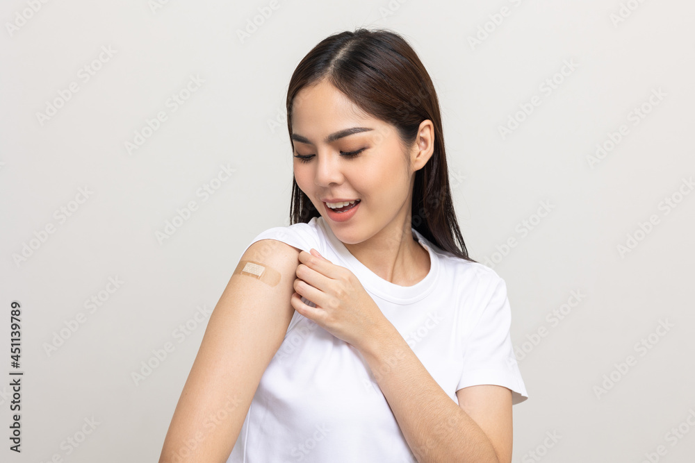 Vaccination. Young beautiful asian woman getting a vaccine protection the coronavirus. Smiling happy female showing arm with bandage after receiving vaccination. On isolated white background. Vaccination. Young beautiful asian woman getting a vaccine protection the coronavirus. Smiling happy female showing arm with bandage after receiving vaccination. On isolated white background.