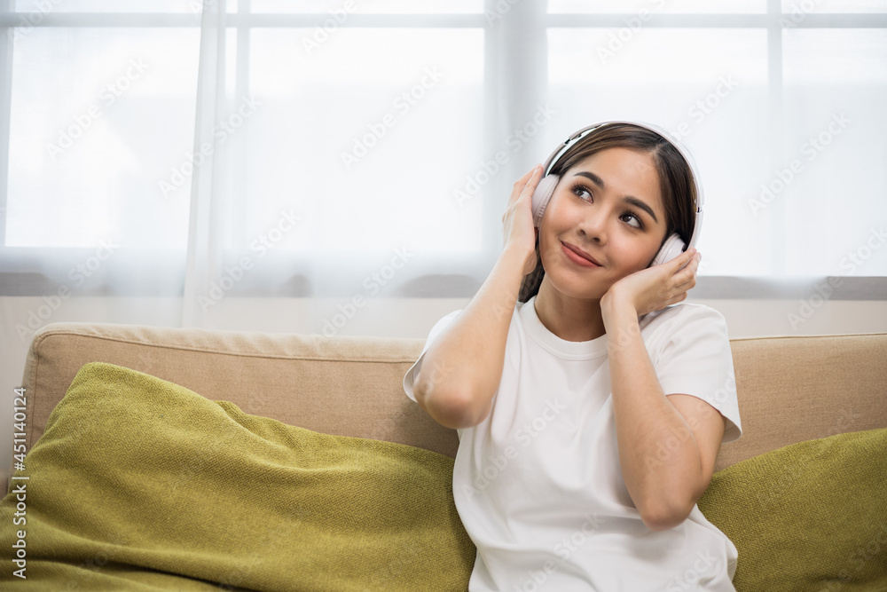 Relaxing time on sofa. Beautiful young asian woman sitting on sofa she choose music from smartphone take a rest and listening song with headphone. Lifestyle in living room at house in the morning. Relaxing time on sofa. Beautiful young asian woman sitting on sofa she choose music from smartphone take a rest and listening song with headphone. Lifestyle in living room at house in the morning.