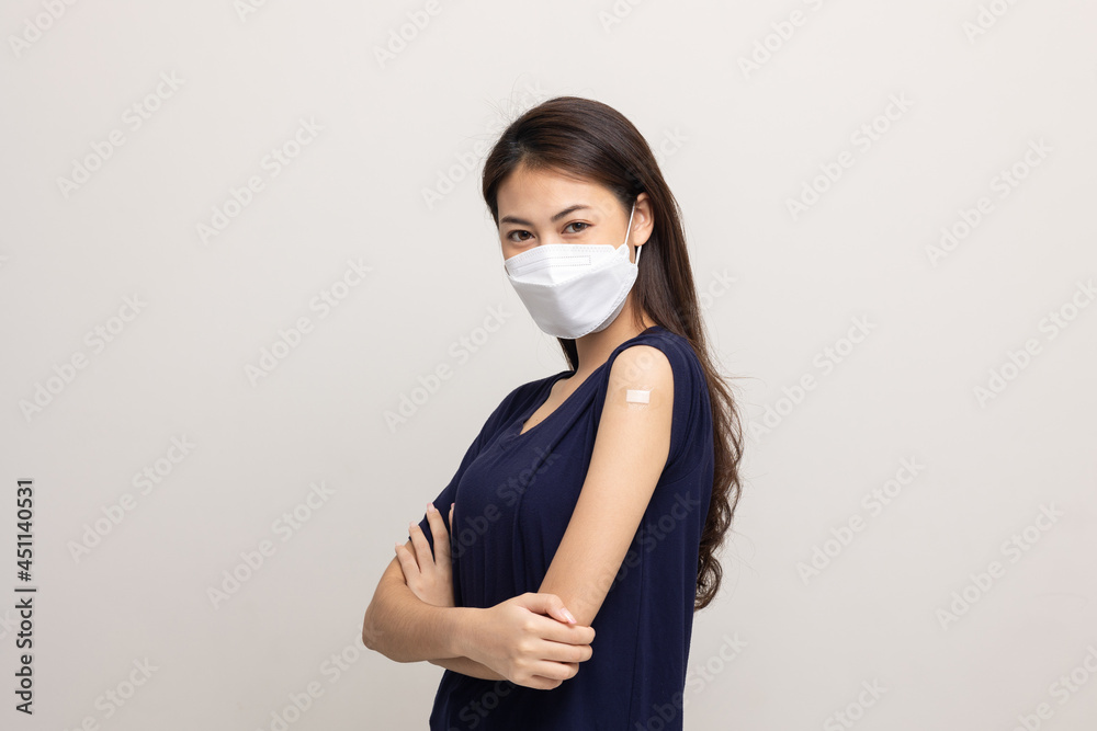 Young beautiful asian woman wearing mask and getting a vaccine protection the coronavirus. Happy female showing arm with bandage after receiving vaccination on isolated white background. Young beautiful asian woman wearing mask and getting a vaccine protection the coronavirus. Happy female showing arm with bandage after receiving vaccination on isolated white background.