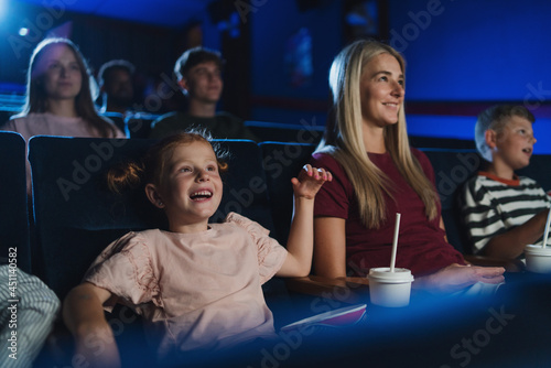 Mother with happy small children in the cinema, watching film.