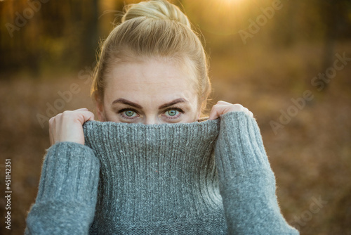 Woman covers part of her face with a sweater. He looks at the camera. Сoncept of abuse, victims, harassment. Idea of psychology, coaching, depression, apathy