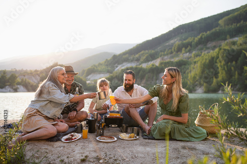 Happy multigeneration family on summer holiday trip, barbecue by lake. photo