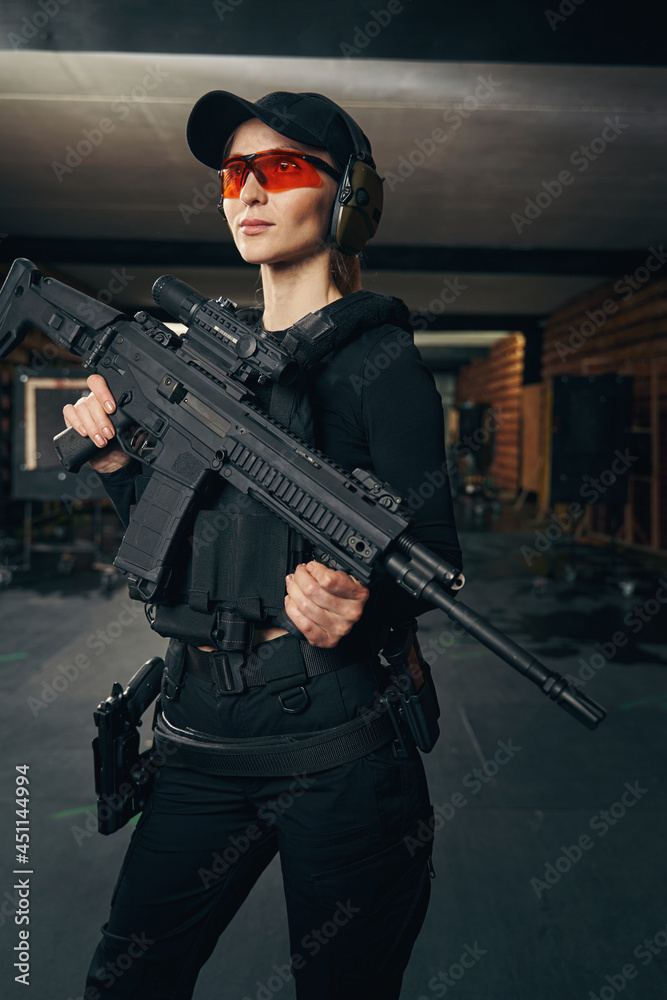 Woman with a firearm standing at an indoor shooting range Woman with a firearm standing at an indoor shooting range