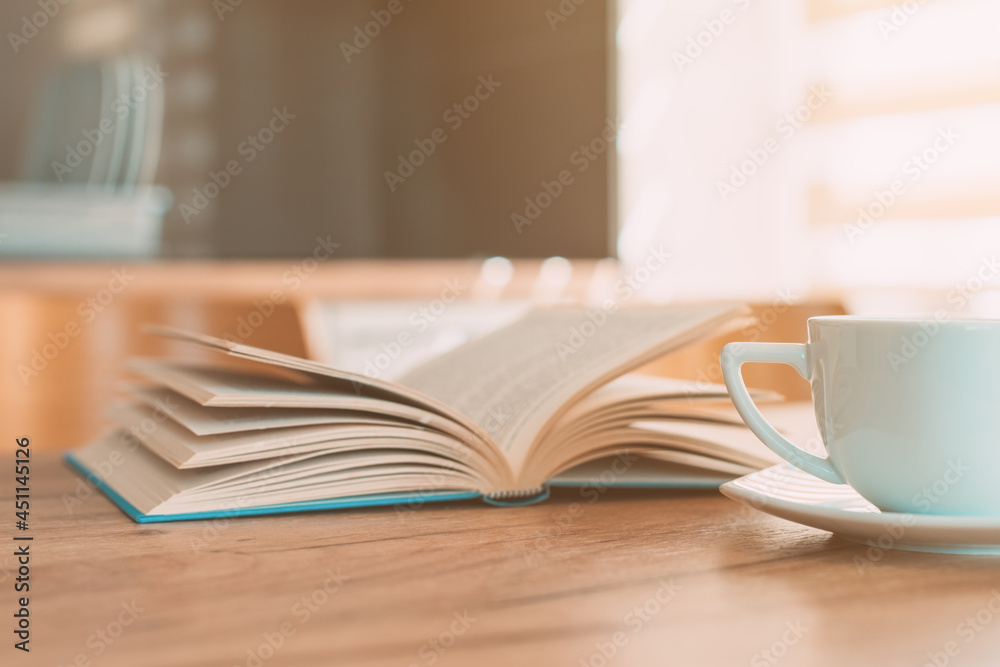 Open book and coffee cup on the table, reading at home in the morning Open book and coffee cup on the table, reading at home in the morning