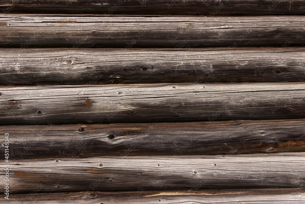 The wall of an old wooden house made of darkened weathered logs. Traditional Russian log hut. The wall of an old wooden house made of darkened weathered logs. Traditional Russian log hut.