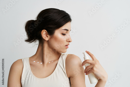 woman in white t-shirt with lotion in hands cosmetics clean skin close-up
