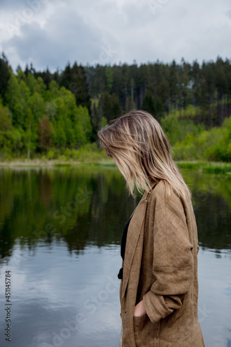 Beautiful woman in brown jacket stay next to lake in autumn time © Masson