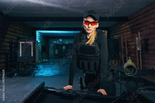 Calm female sniper in a bulletproof vest looking ahead photo