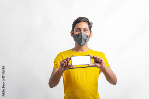 young indian man wearing mask and showing Smartphone