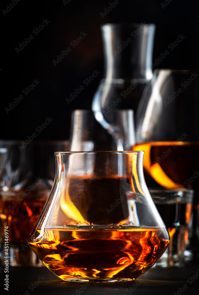 Fototapeta premium Strong alcoholic drinks, spirits and distillates iset in glasses: cognac, scotch, whiskey and other. Black bar counter background