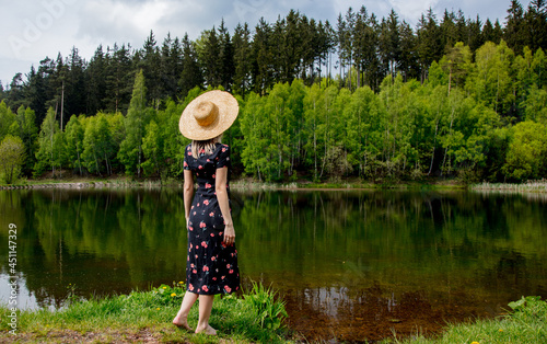 Beautiful woman in drass and hat stay next to lake in autumn time photo