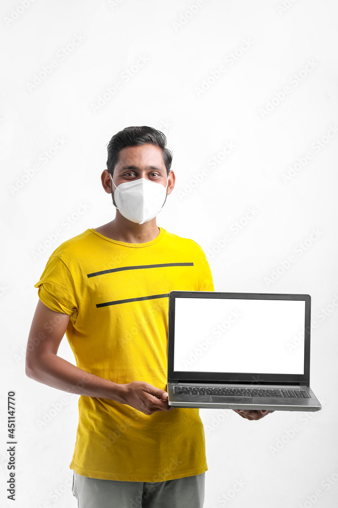 Young indian man showing laptop screen over white background.