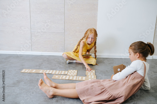 Little girls sitting on the floor, playing in a giant handmade cardboard domino photo