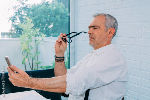 mature man with mobile phone and presbyopia or myopia photo