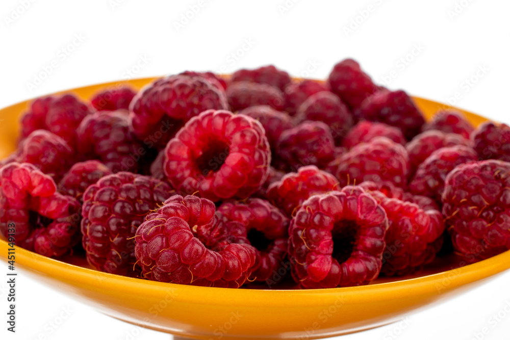 Several berries of ripe red raspberries on a yellow ceramic saucer, close-up, isolated on white. Several berries of ripe red raspberries on a yellow ceramic saucer, close-up, isolated on white.