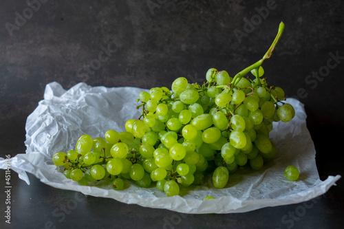 Ripe green sultana raisin with water drops. Fresh grapes on the dark background. Minimalistic grapes close-up shot.  photo