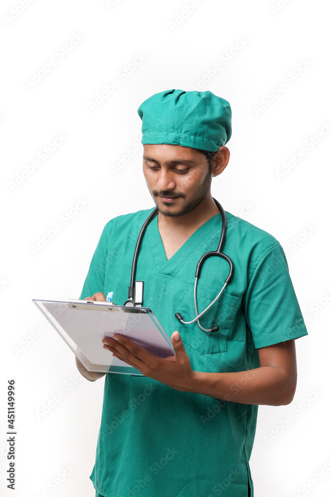 Young indian male doctor in uniform with stethoscope taking notes in notepad over white background. Young indian male doctor in uniform with stethoscope taking notes in notepad over white background.