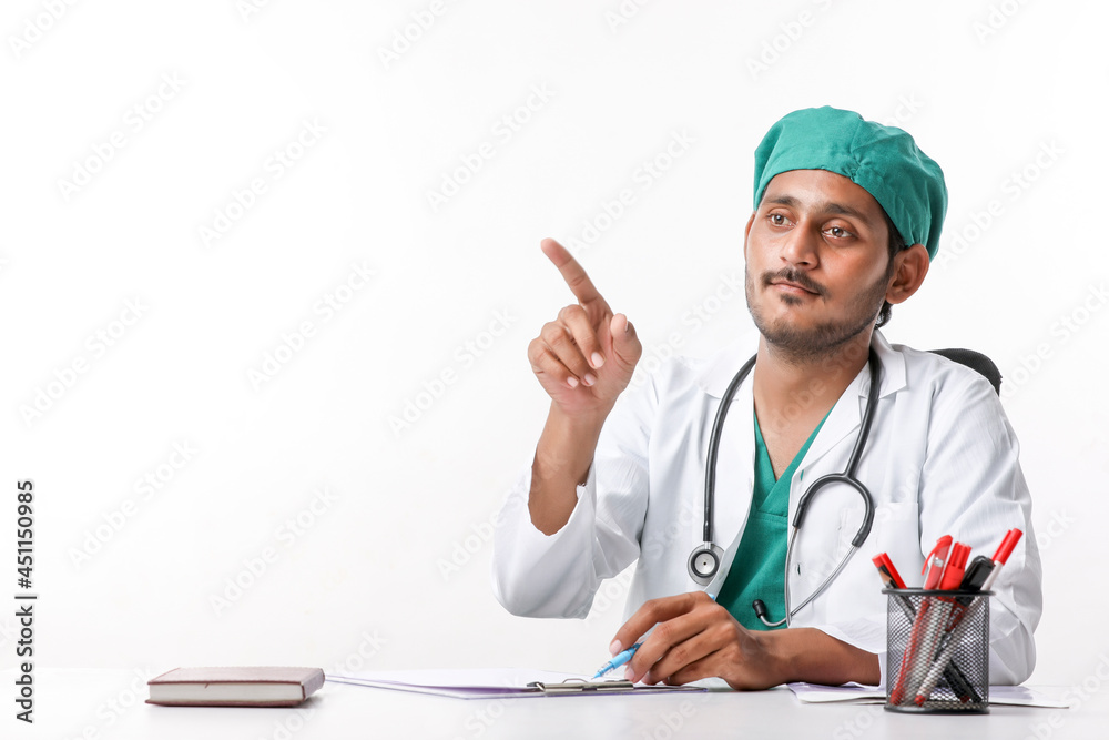 Young indian male doctor in uniform and pointing with hand at clinic. Young indian male doctor in uniform and pointing with hand at clinic.