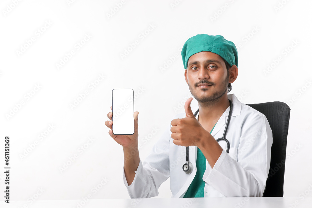 Young indian doctor showing smartphone screen over white background. Young indian doctor showing smartphone screen over white background.