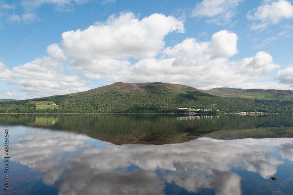 View of Loch Rannoch, a freshwater loch in Pitlochry in Scotland. The village Kinloch Rannoch is seen on the other side in the distance. Water reflection. Soft focus.