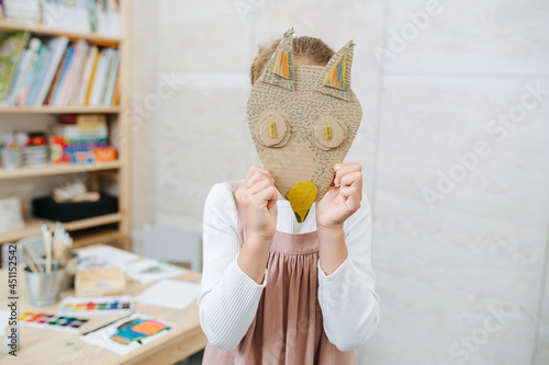 Little girl holdng cardboard handmade fox mask over her face. At a child learning center. photo