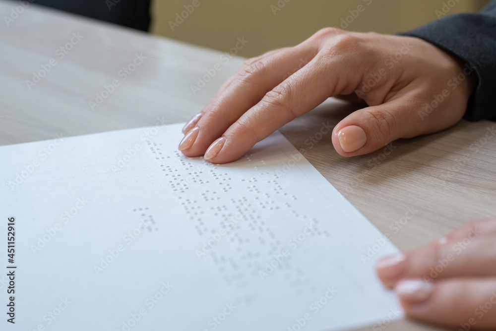Close-up woman reads the text to the blind. Woman's hands on paper with braille code. Close-up woman reads the text to the blind. Woman's hands on paper with braille code.