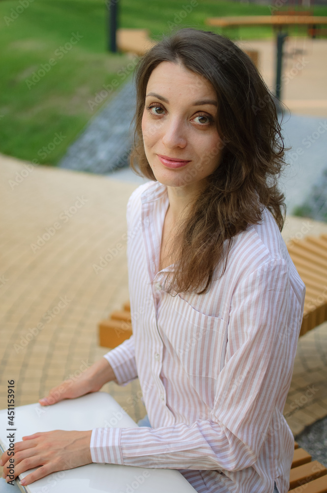 Female portrait of young woman with silver laptop, businesswoman is posing with digital tablet outside on modern building background, remote job