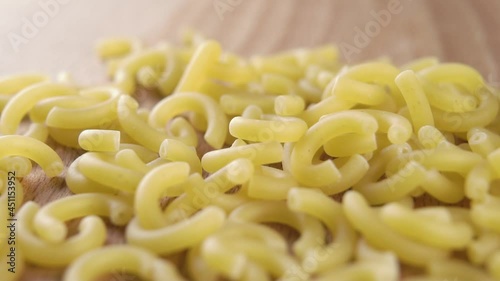 Falling dry uncooked italian gobbetti pasta on a wooden table in slow motion. Macro. Traditional Italian Mediterranean cuisine. Raw macaroni photo