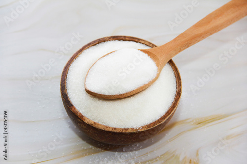 white granulated sugar in a wooden spoon